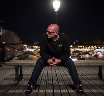 Photo de l'artiste Dj Duke assis sur un banc à Paris.