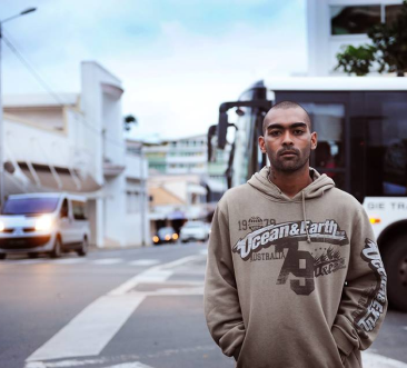 Photographie de l'artiste Calédonien Kydam posant devant un bus.